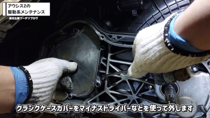 クランクケースカバーをマイナスドライバーで外しています。