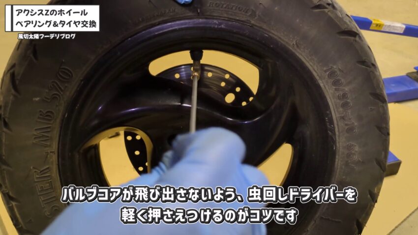フロントタイヤのバルブコアを虫回しドライバーを使って取り外しています