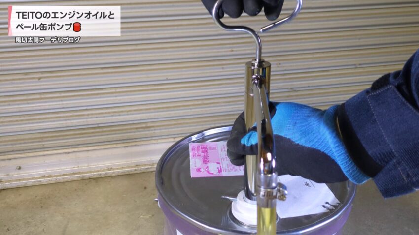 ペール缶ポンプの本体を手で固定しながらオイルを吐出する