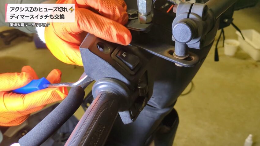 内装剥がしでディマースイッチのツメを押さえて取り外す様子