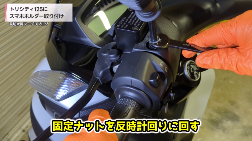 左側のミラーの固定ナットを緩めている様子